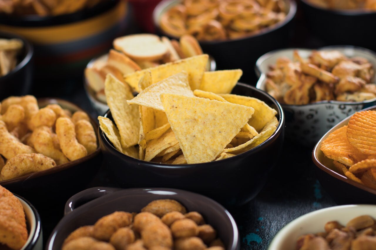 Salty snack including peanuts, potato chips and pretzels served as party food in bowls