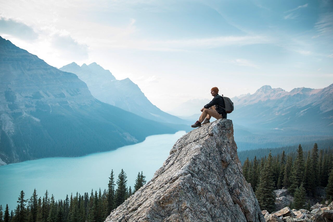A young man sitting on a rock overlooking Peyto Lake.