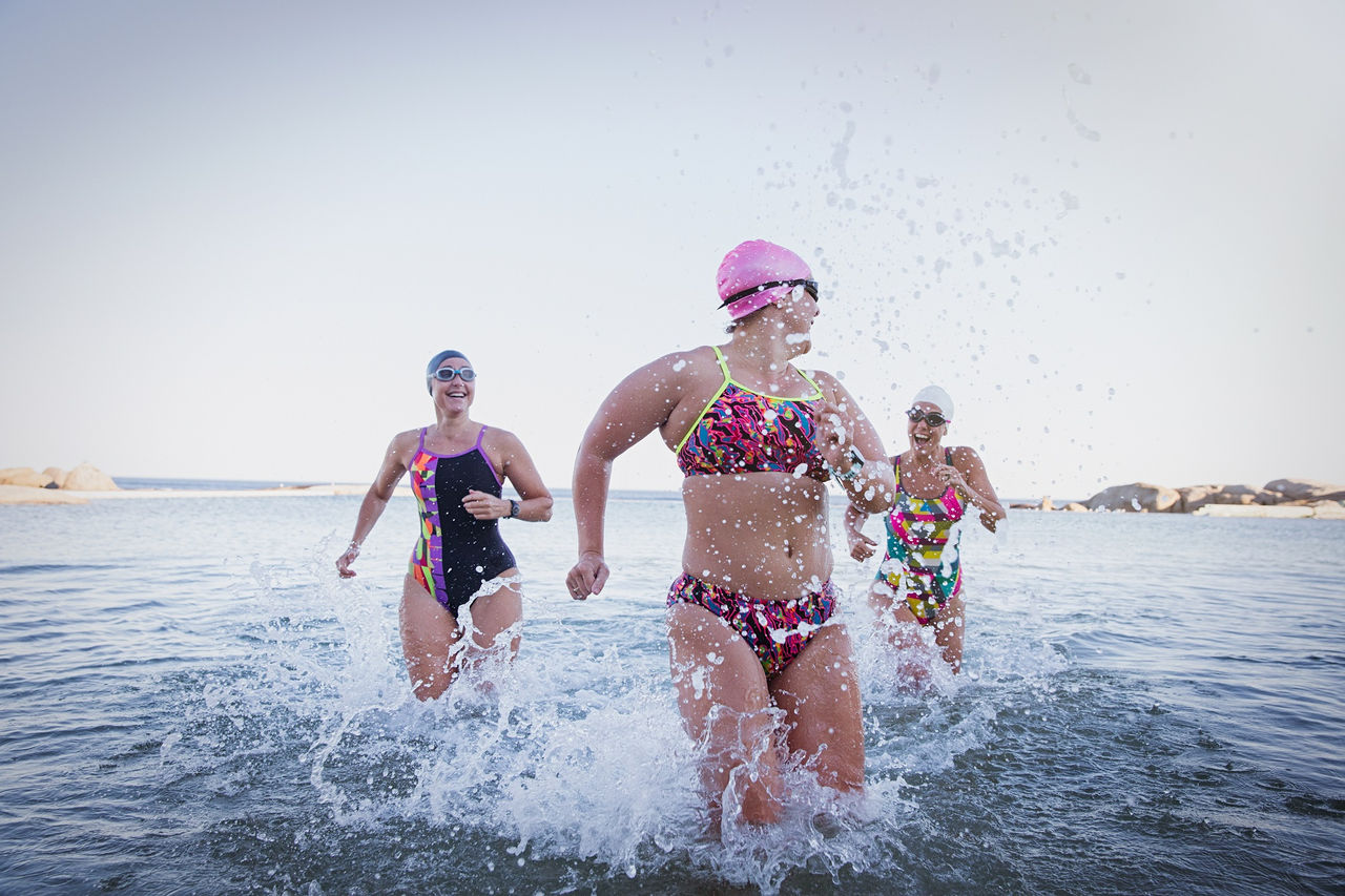 Female open water swimmers running, splashing in ocean surf; Shutterstock ID 2108631962; purchase_order: Masterbrand - Loop 4; job: ; client: ; other: 