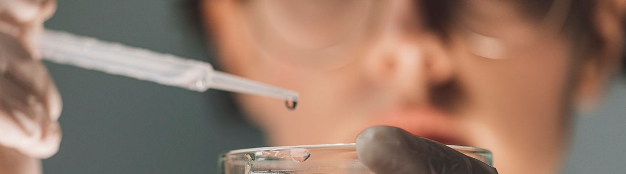 Female lab technician working with strains of bacteria grown in petri dishes