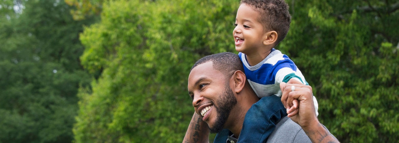 African American father carrying son outdoors