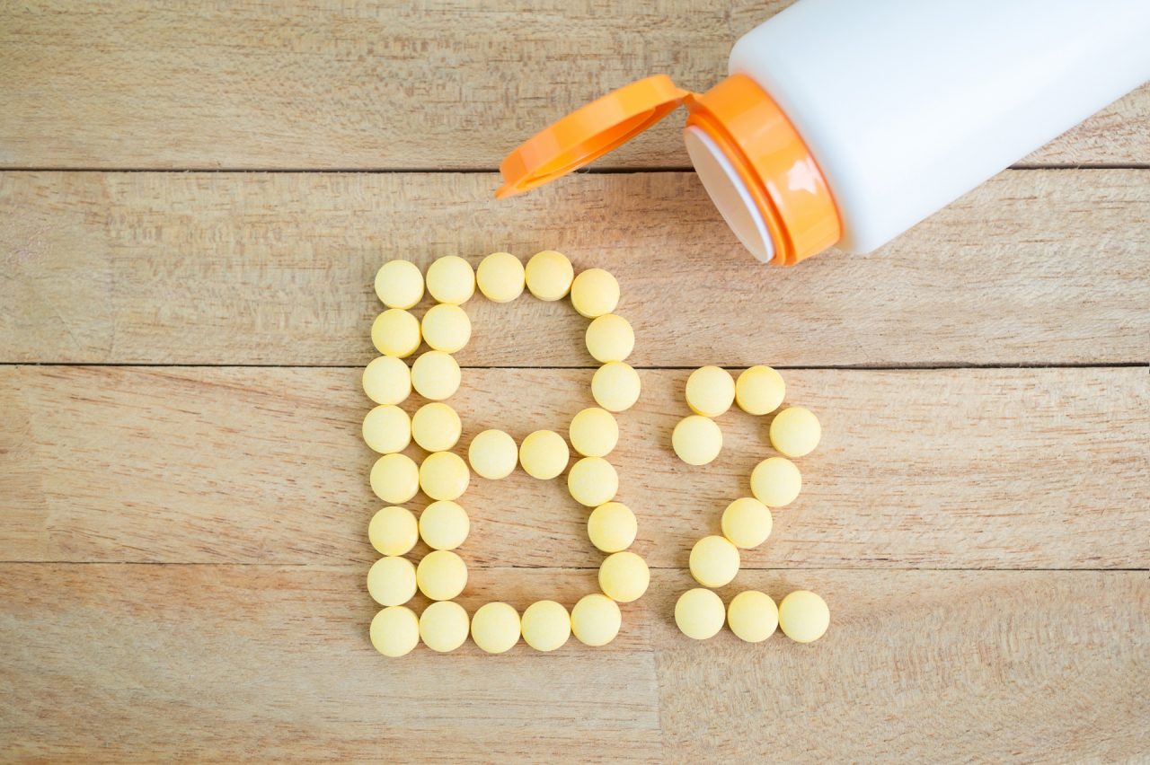 Yellow pills forming shape to B2 alphabet on wood background