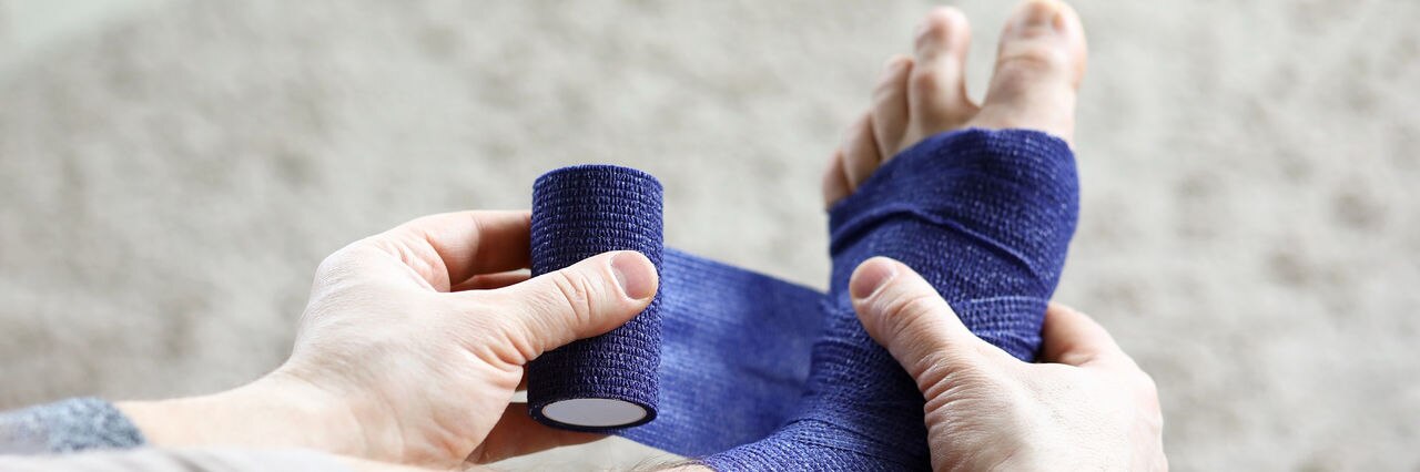Man pulls stretch on his leg with elastic bandage. Prevents repeated injury. Uniform compression in all areas for foot massage effect. Increase blood circulation and relieve pain