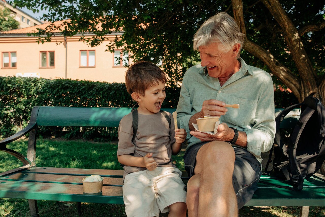 Happy grandfather and grandson enjoying ice cream while sitting on bench; Shutterstock ID 2213915861; purchase_order: TTH_1st round (12 images); job: ; client: ; other: 