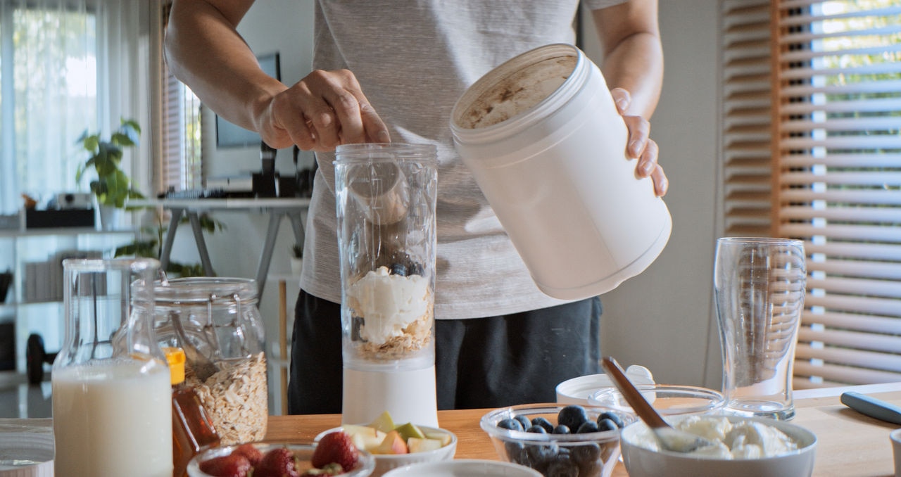 Young adult Asian man prepare and make protein shake drink, mixed fruit cereal juice, using blender mixer. Fitness dietary activity, healthy diet lifestyle, health care nutrition concept