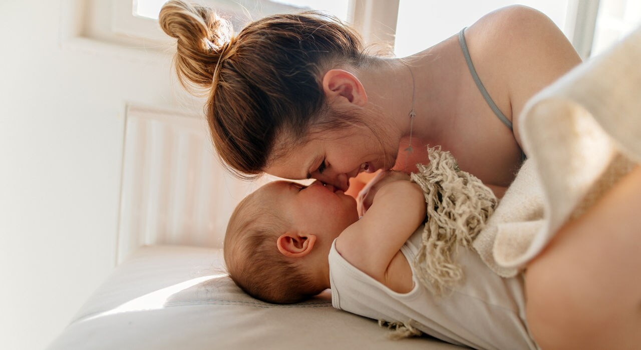 Mom and baby boy cuddling on the bed in the morning