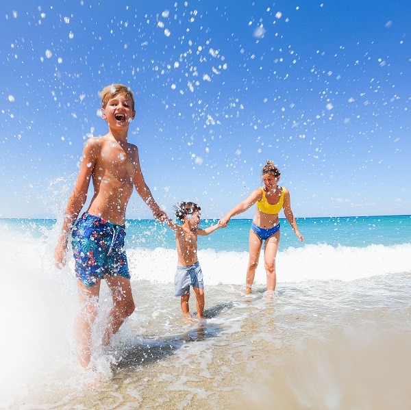 Photo of two young boys and their mom having fun on local beach during summer vacation