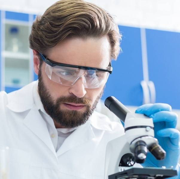 Modern science. Serious intelligent pleasant man sitting at the table and holding a test tube while working in the lab