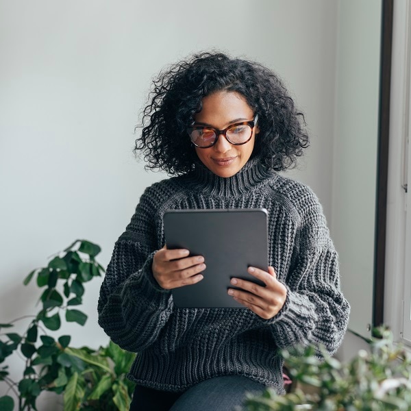 Young woman wearing glasses watching something on her digital tablet (copy space).