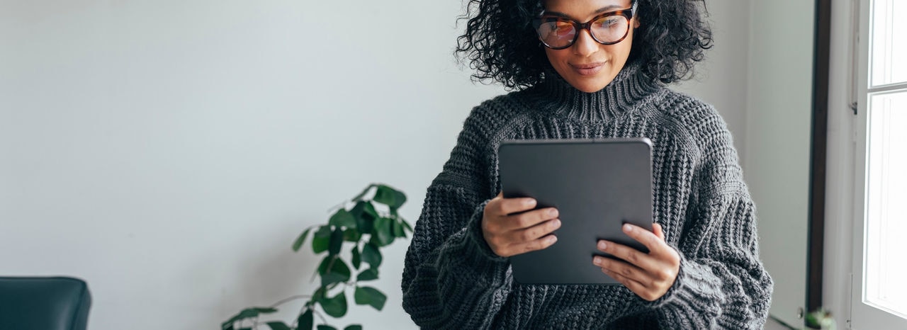 Young woman wearing glasses watching something on her digital tablet (copy space).