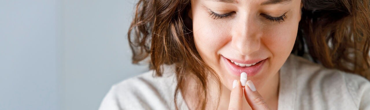 Smiling young woman taking medication at home