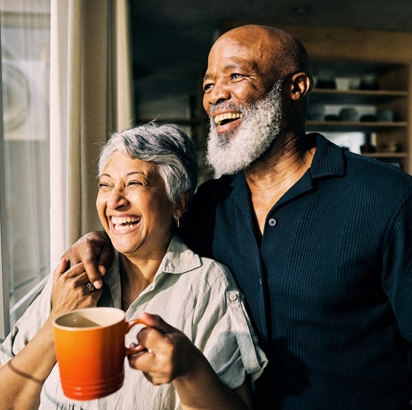 African-American mature couple looking out the window of their home filled with optimism.