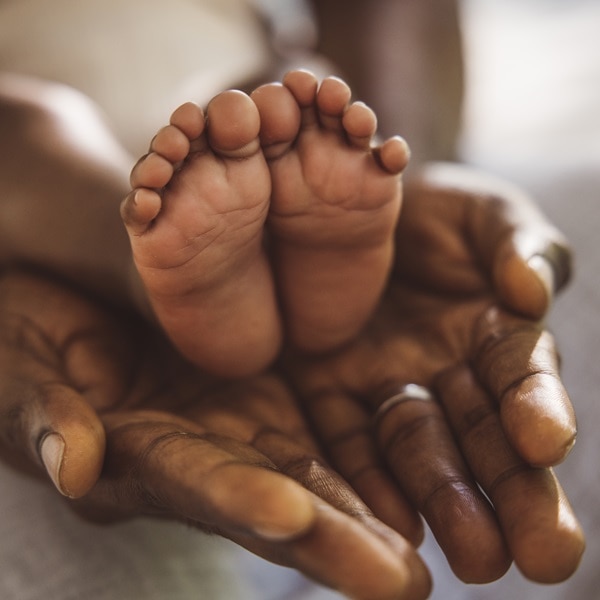 Cropped shot of a father holding her baby’s feet