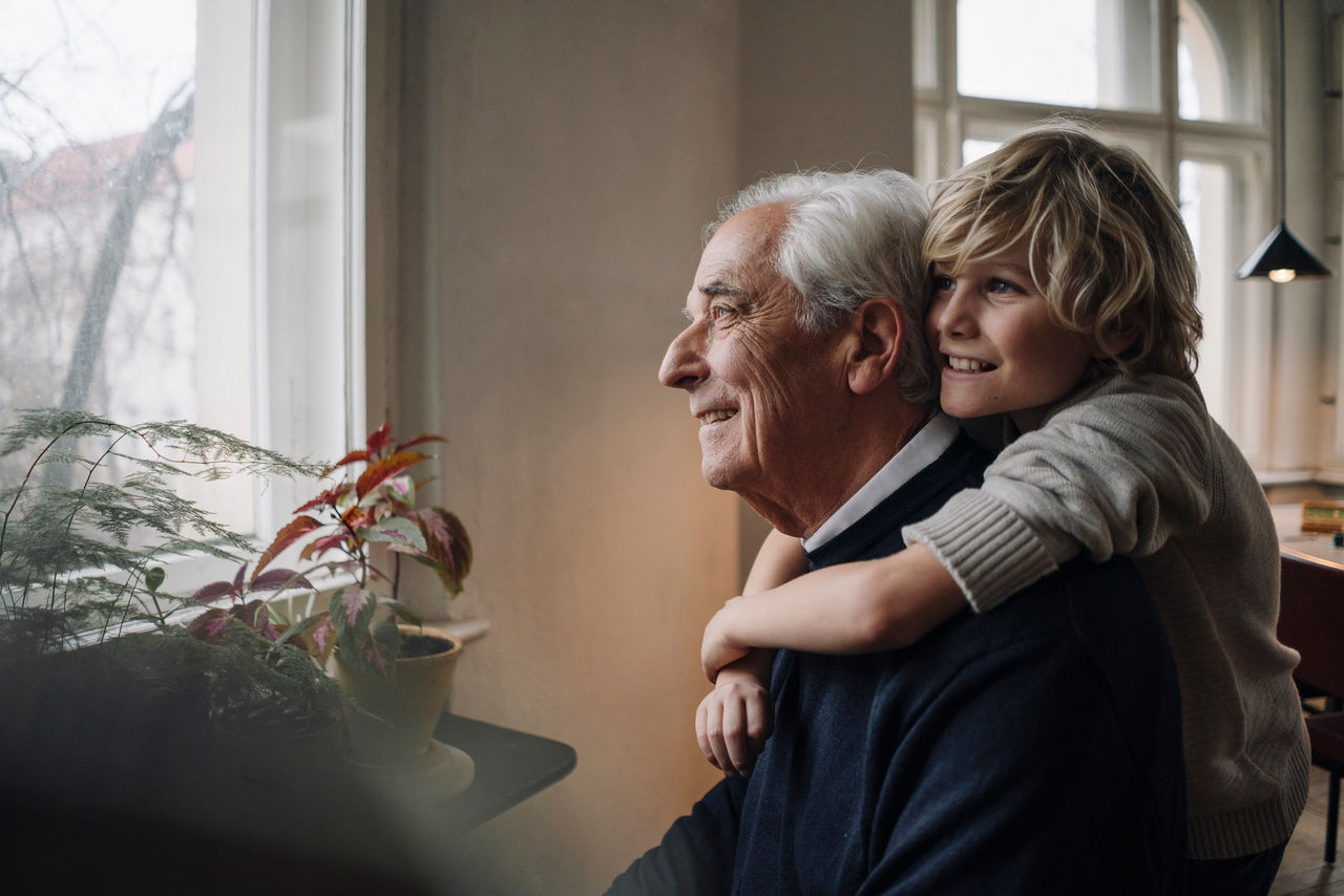 Happy grandson embracing grandfather at home
