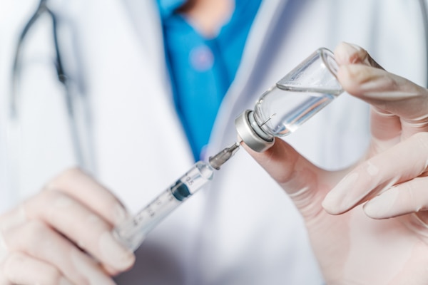 The doctor holding a syringe with Covid-19 vaccines in glass bottle. Covid-19 corona virus treatment concept.