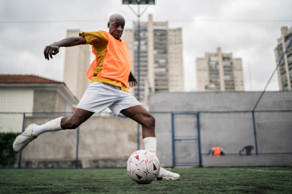 Mature man kicking the soccer ball on the soccer field