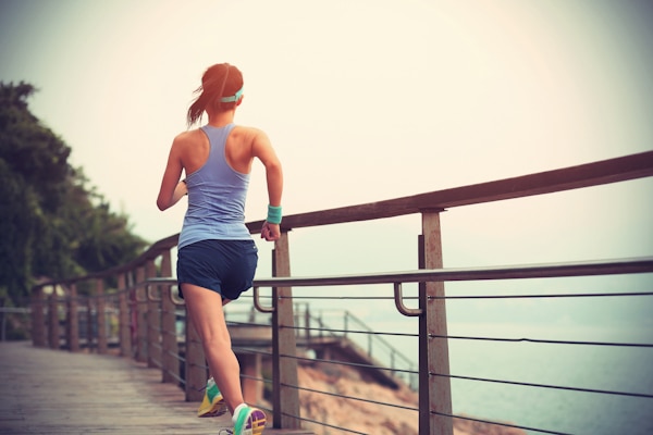 healthy lifestyle young fitness sports woman running on seaside boardwalk