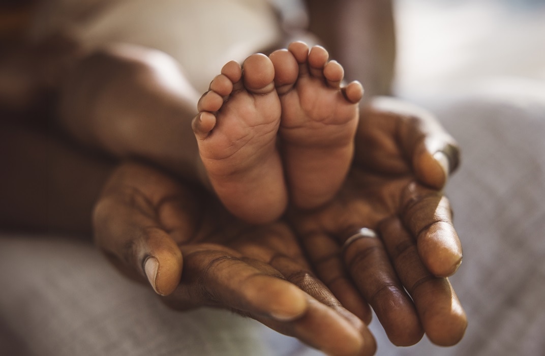 Cropped shot of a father holding her baby’s feet