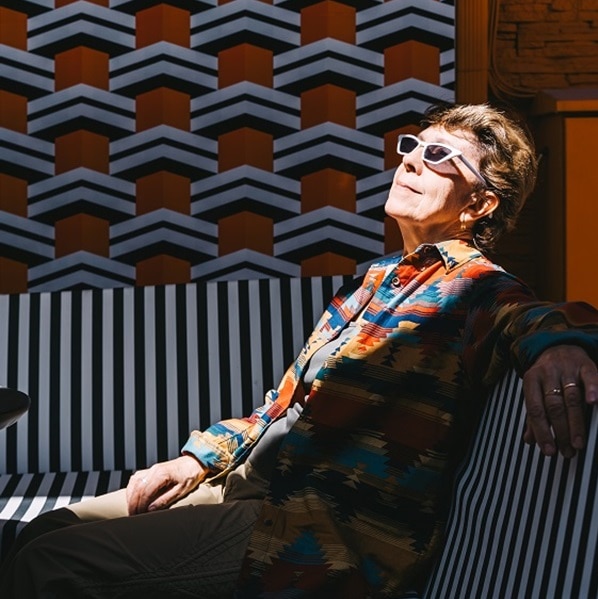 Fashionable mature retired woman in white sunglasses enjoying life in a bright outdoor cafe on a sunny day.